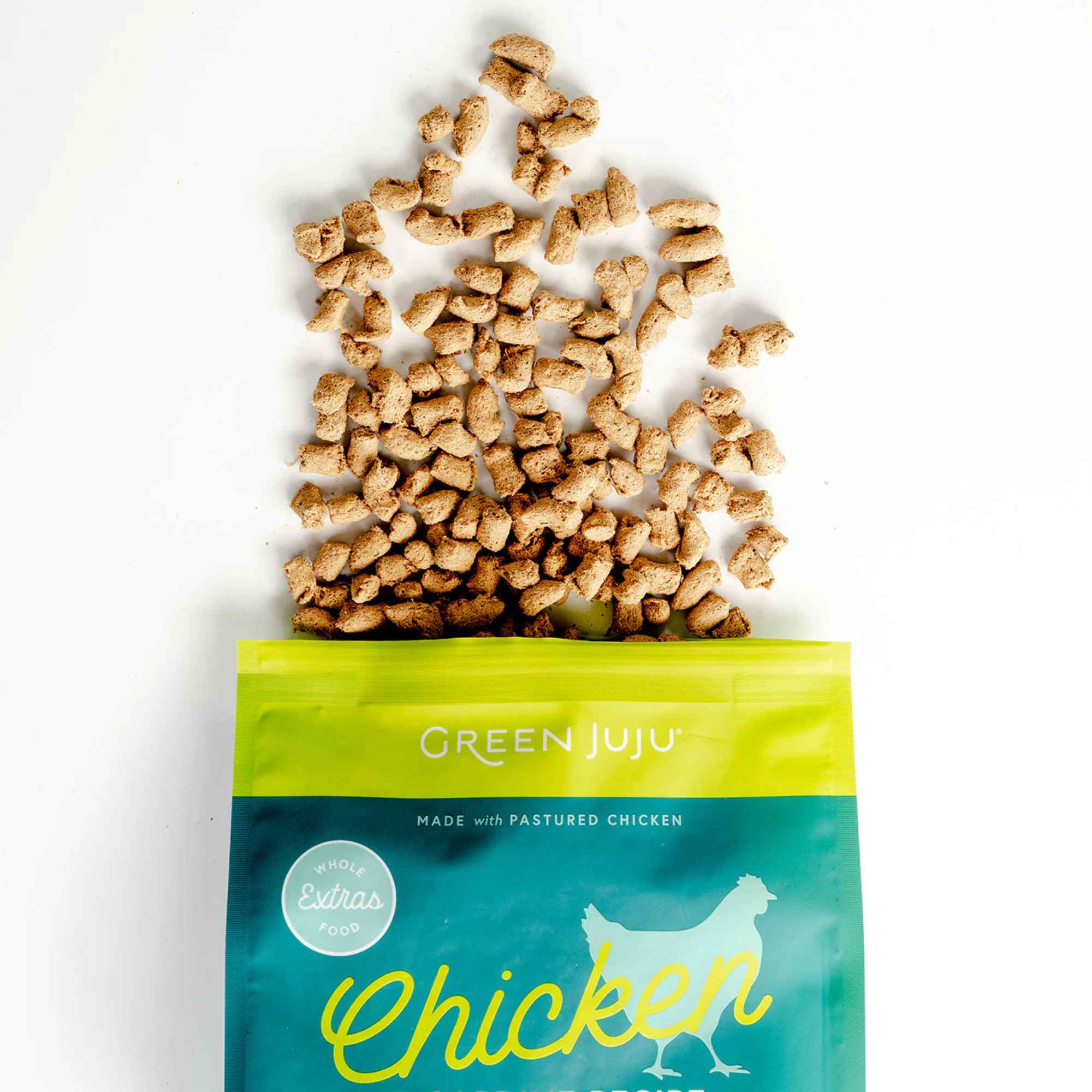 Green Juju freeze dried raw chicken and sardine pet food packaging with scattered food on a white background